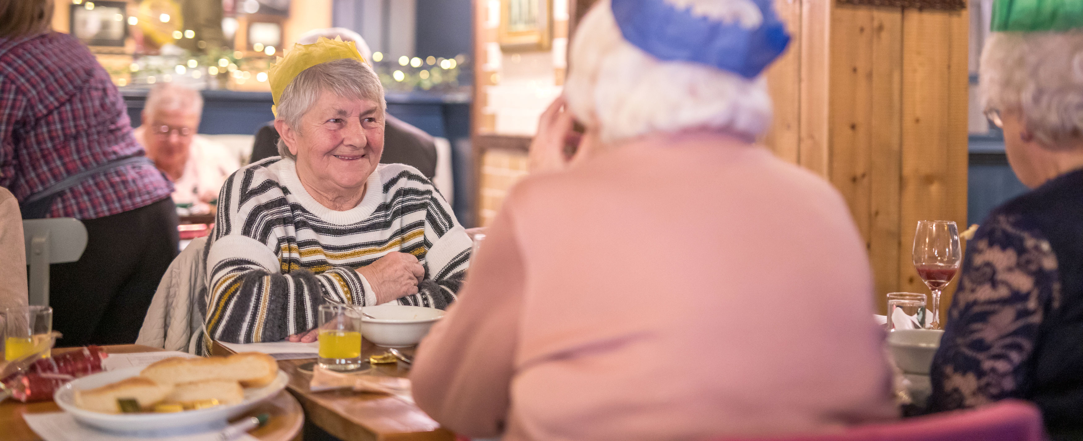 Three women chatting whilst wearing Christmas hats