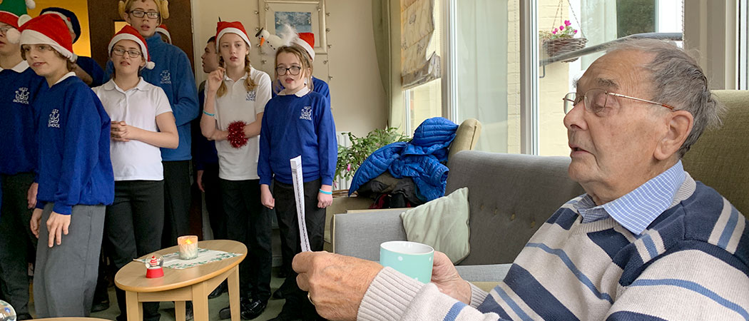 Older man singing with choir of school children